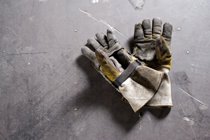 Worn work gloves lying on concrete floor