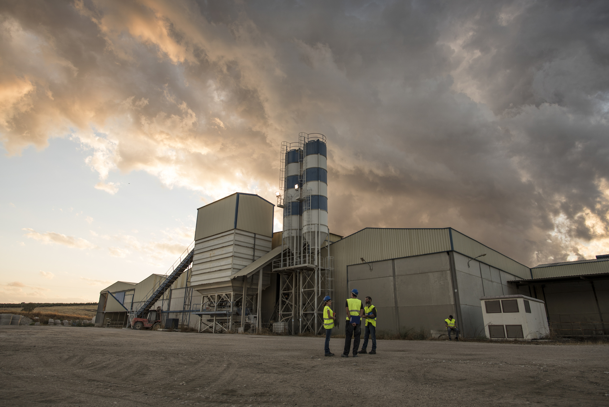 workers in a cement factory work outdoors with a tablet planning their work and checking concrete structures