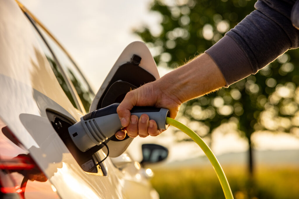 Man inserts a power cord into an electric car for charging