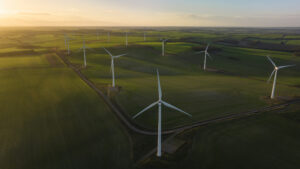 Aerial/Drone view of a wind farm with multiple wind turbines at sunrise