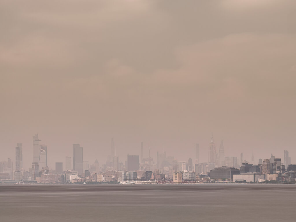 Long exposure of Hudson Yards and Midtown Manhattan across the Hudson River on a hazy day where the Canadian fire smoke engulfs the city including the Empire State Building and the Chrysler Building