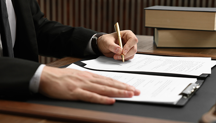 Lawyer working with documents at wooden table indoors, closeup
