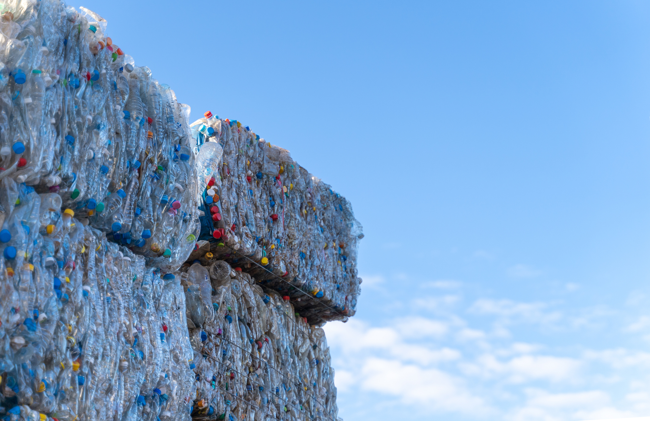 Recyclable plastic materials stacked at waste sorting plant and sky