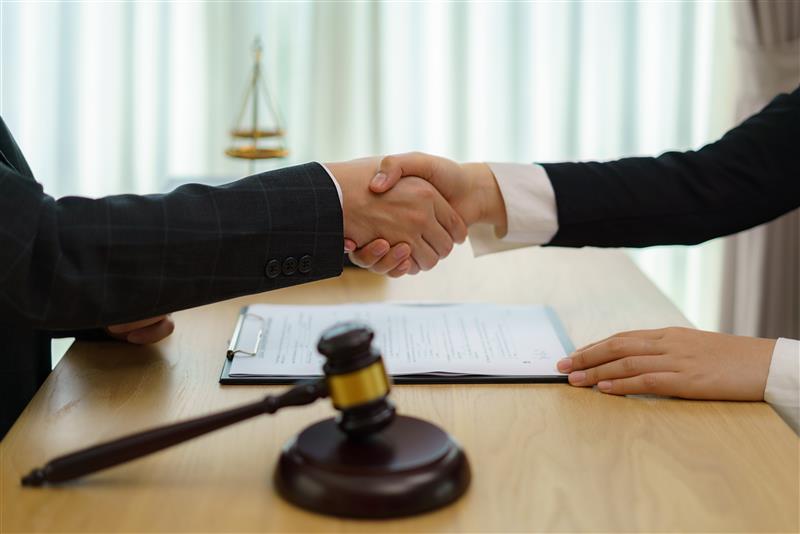 two people shaking hands near a gavel