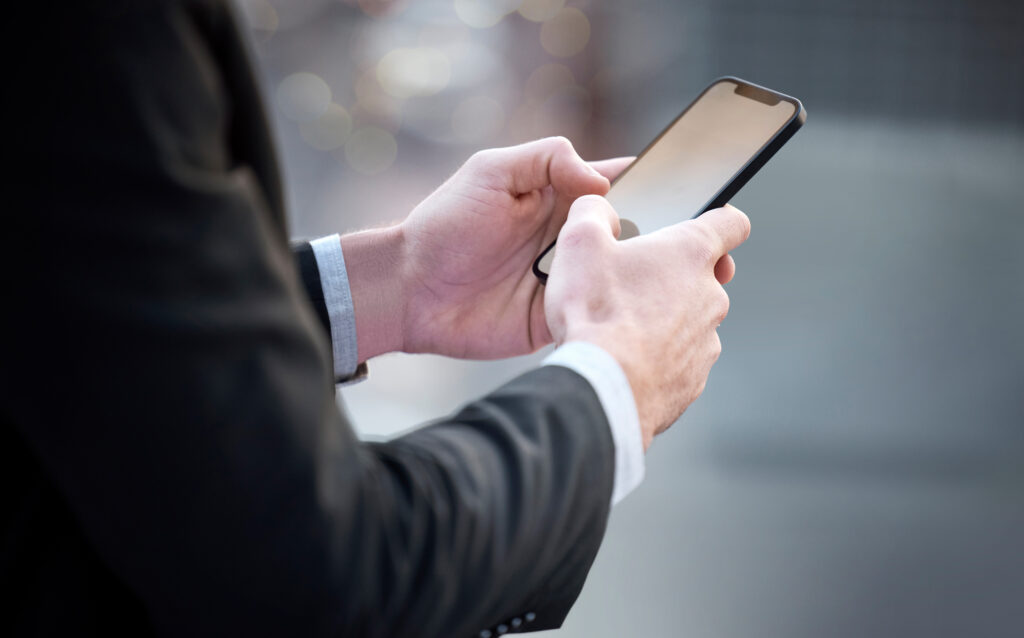 Cropped shot of an unrecognisable businessman standing in the city and using his cellphone