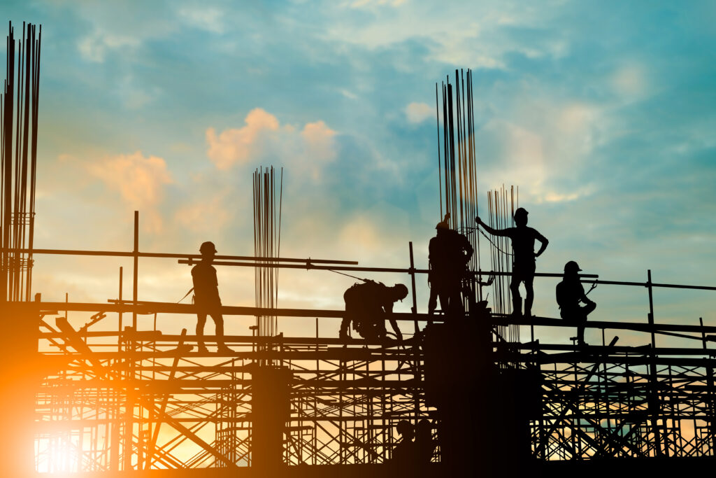 Silhouette of engineer and construction team working safely on scaffolding on high rise building.